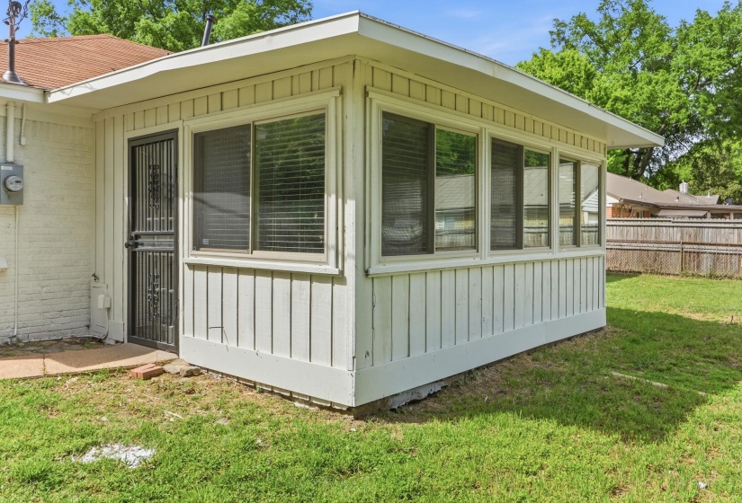View of side of property with a sunroom, board and batten siding, and brick siding