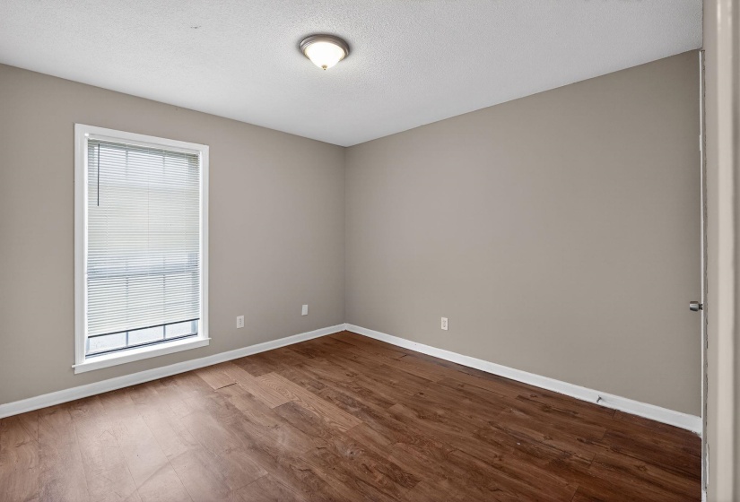 Empty room featuring dark wood-type flooring and a textured ceiling