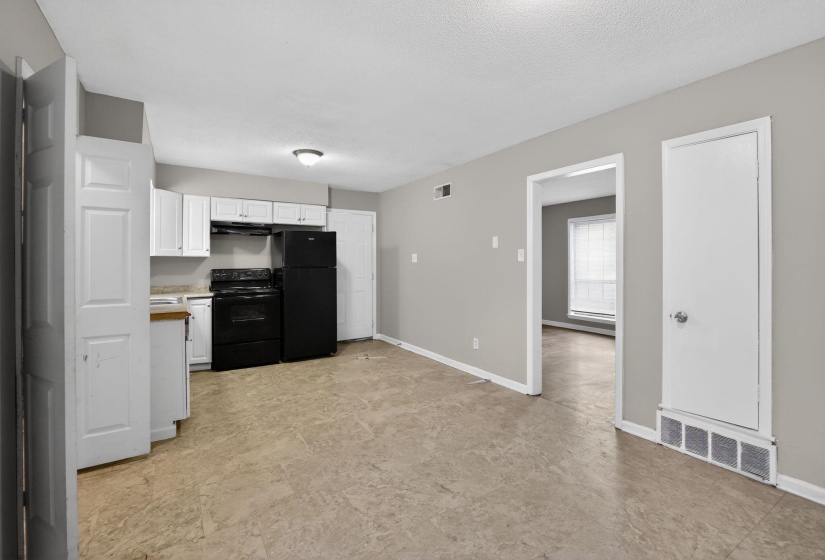 Kitchen with white cabinetry, black appliances, light countertops, and a textured ceiling
