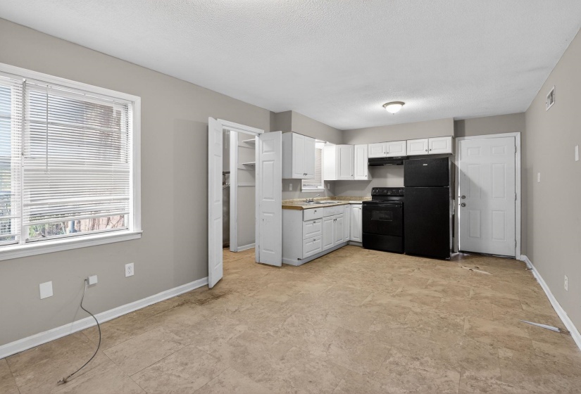 Kitchen with black appliances, white cabinets, light countertops, and a textured ceiling