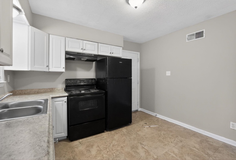 Kitchen with black appliances, white cabinets, light countertops, and a textured ceiling