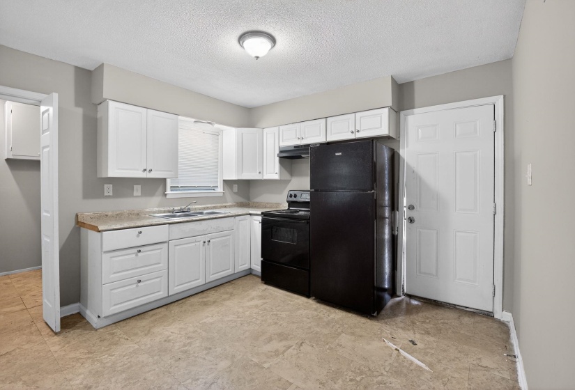 Kitchen featuring black appliances, light countertops, white cabinets, and a textured ceiling