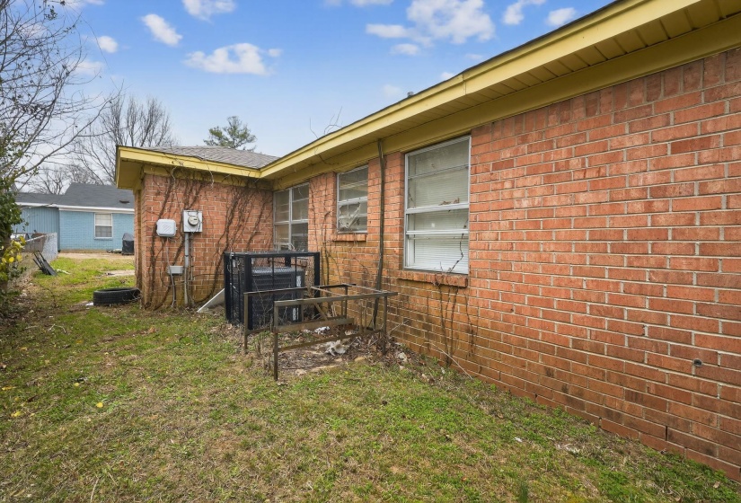 View of side of property with brick siding and a lawn