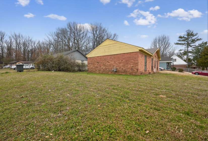View of side of property featuring brick siding and a lawn