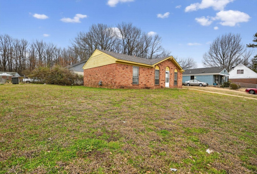 View of side of home with brick siding and a lawn