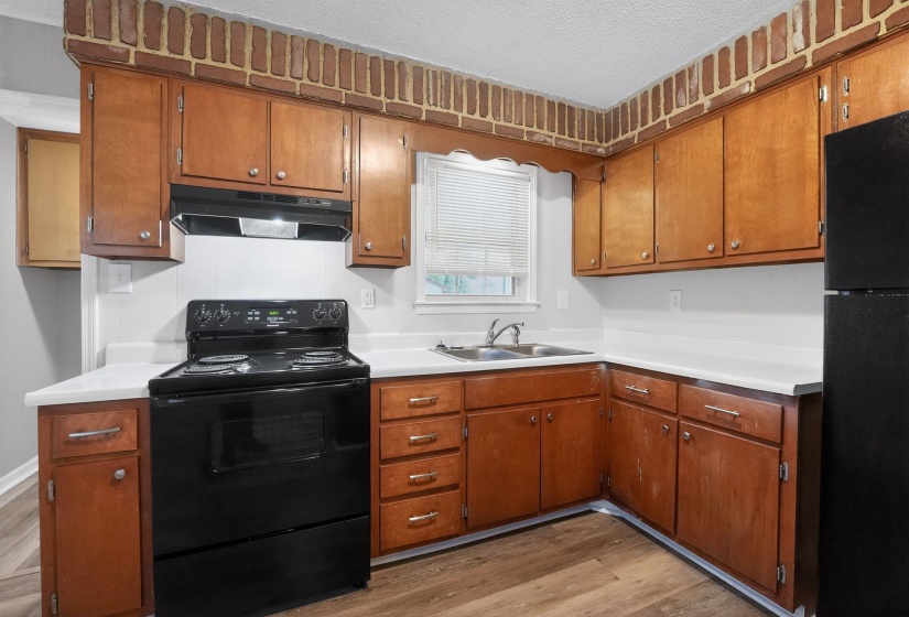 Kitchen featuring black appliances, light countertops, wood finish cabinets, light wood-style flooring, and a textured ceiling