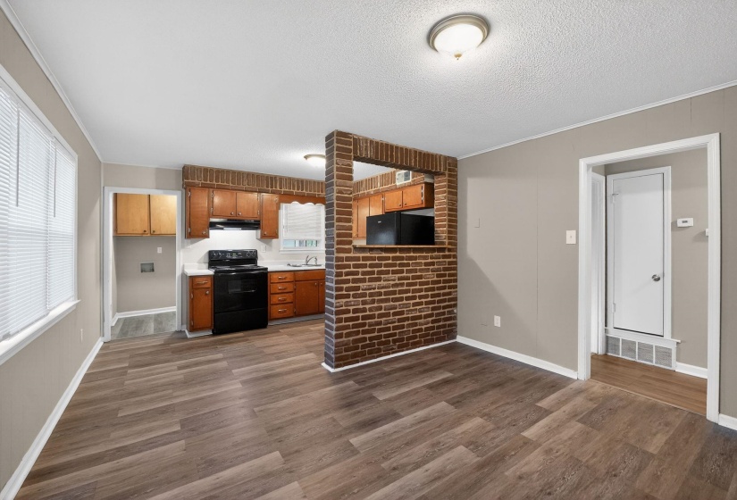 Kitchen featuring black appliances, light countertops, ornamental molding, wood finish cabinetry, and dark wood finished floors