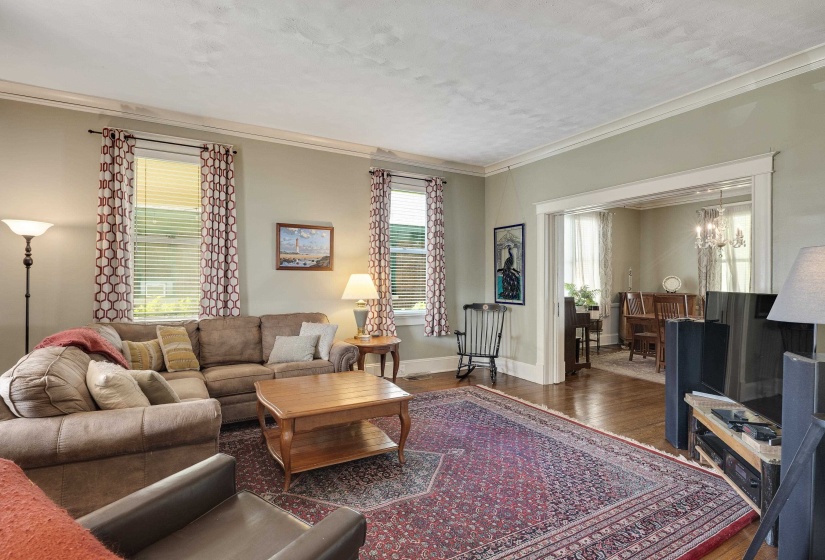 Living area with hardwood / wood-style floors, ornamental molding, hanging lights, and a textured ceiling
