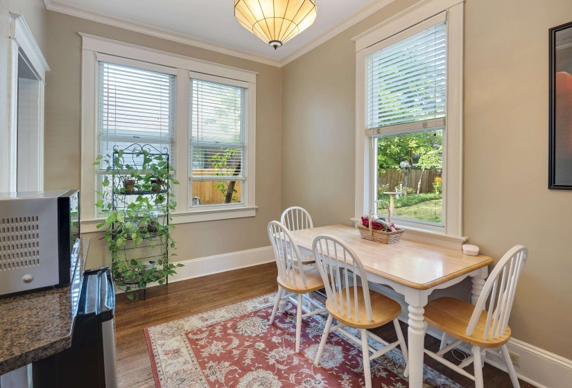 Dining room with ornamental molding and dark wood-style floors