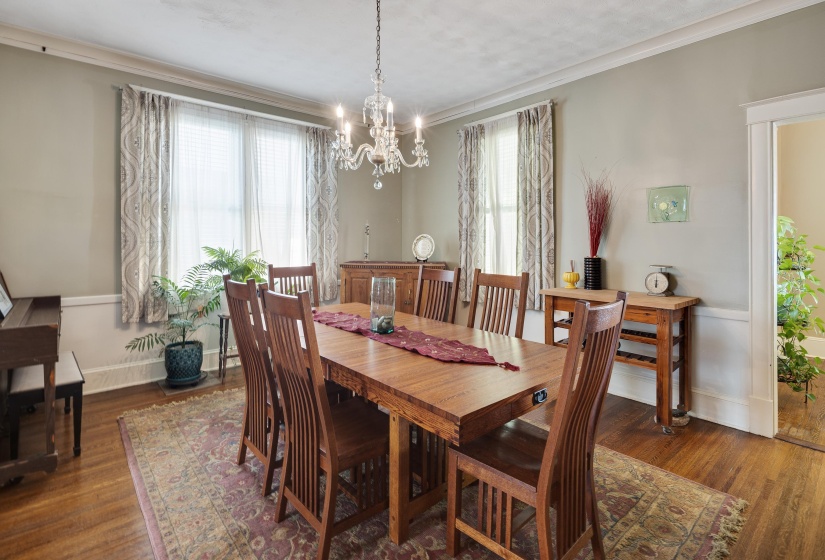 Dining space with dark wood finished floors, a chandelier, and crown molding