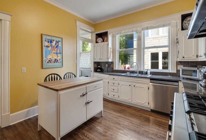 Kitchen with stainless steel appliances, crown molding, extractor fan, tasteful backsplash, and dark wood-type flooring