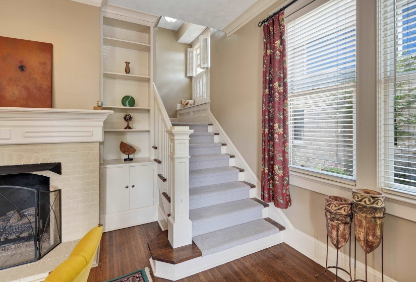 Stairs with wood finished floors, healthy amount of natural light, and a fireplace