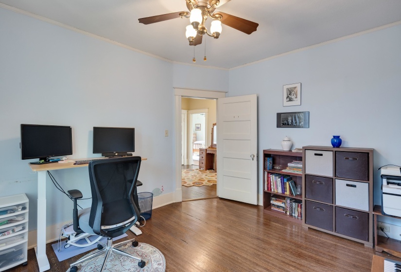 Home office with ceiling fan, crown molding, and dark wood-style floors