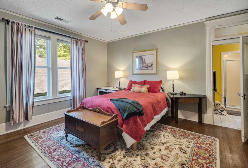 Bedroom featuring dark wood-type flooring, a textured ceiling, ceiling fan, and ornamental molding