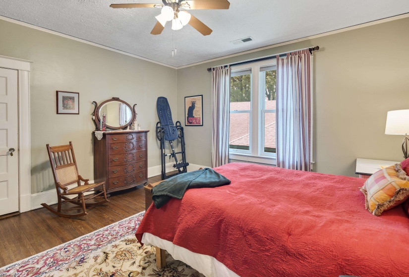 Bedroom with dark wood-style floors, ornamental molding, a ceiling fan, and a textured ceiling