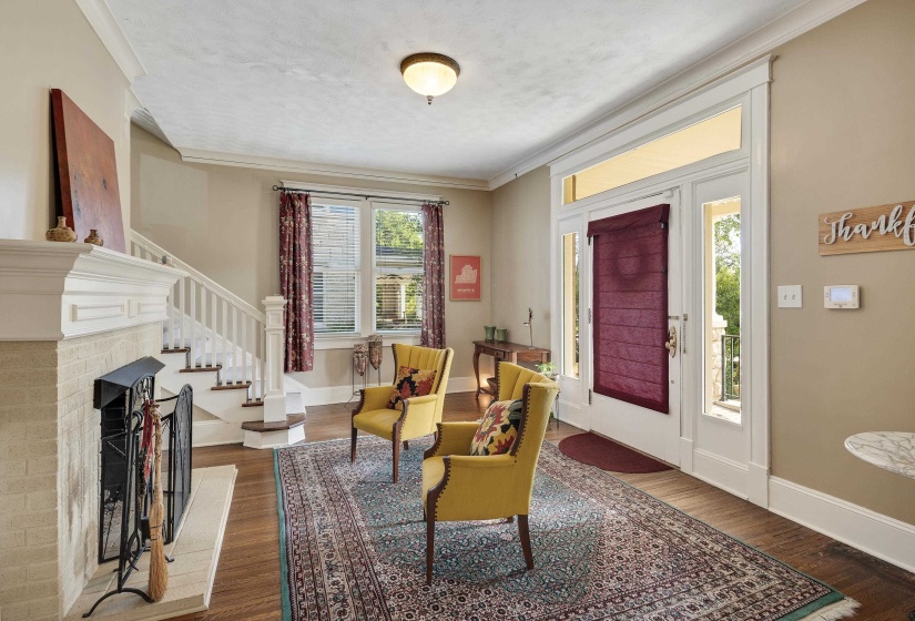 Foyer entrance featuring dark wood-style flooring, ornamental molding, and a brick fireplace