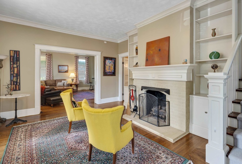 Living area featuring built in shelves, dark wood-style floors, a fireplace, crown molding, and a textured ceiling