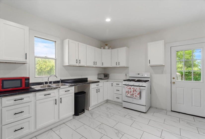 Kitchen featuring gas range gas stove, white cabinetry, and light marble finish floors