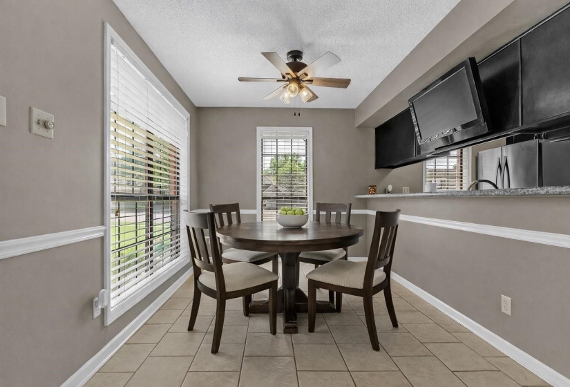 Dining space with ceiling fan, a textured ceiling, and light tile patterned floors