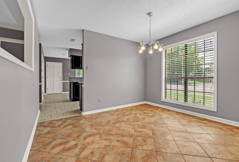 Unfurnished room featuring a chandelier, a textured ceiling, and light tile patterned flooring