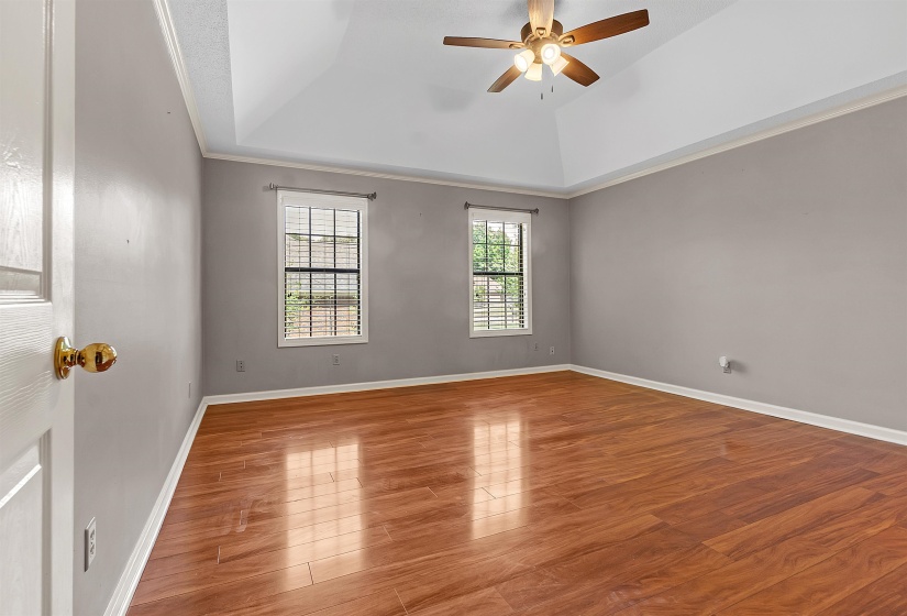 Unfurnished room with a ceiling fan, wood finished floors, and a tray ceiling