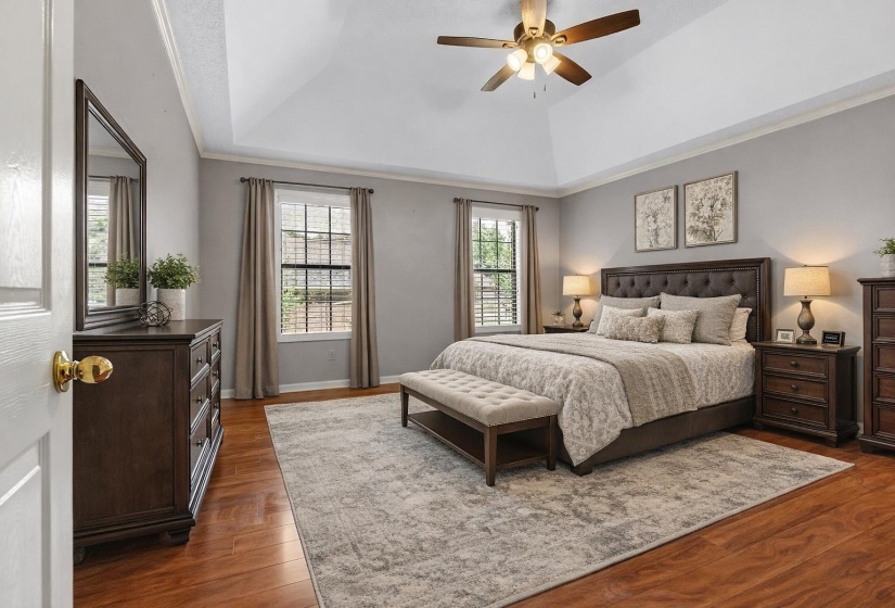 Bedroom with a raised ceiling, dark wood finished floors, and ceiling fan