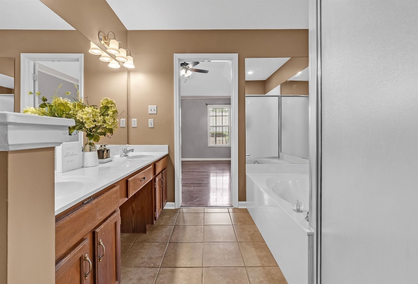 Bathroom featuring double vanity, light tile patterned floors, and a garden tub