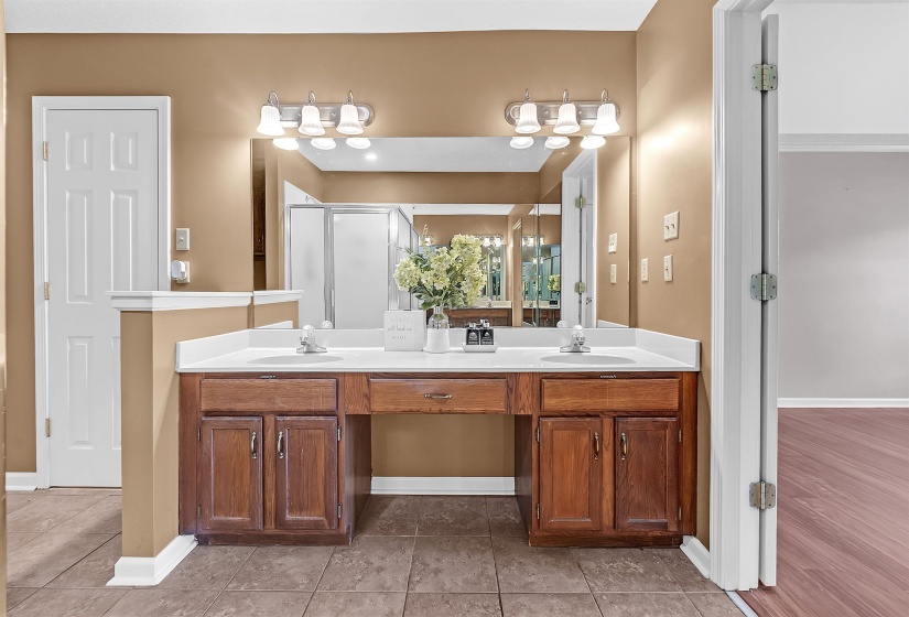 Full bathroom featuring double vanity, light tile patterned floors, and a stall shower