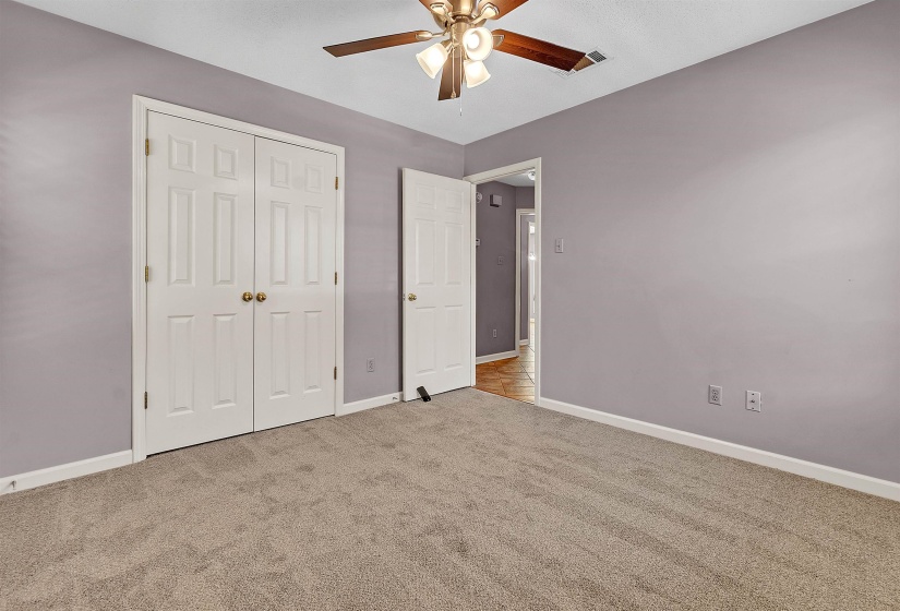 Unfurnished bedroom with light colored carpet, ceiling fan, and a closet
