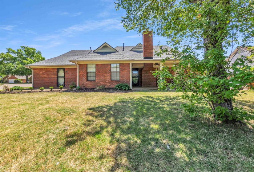 View of front of house featuring a chimney, a front lawn, brick siding, and roof with shingles