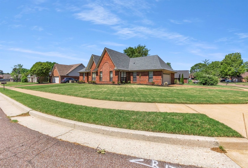 View of front of house featuring a garage, brick siding, a front yard, roof with shingles, and driveway
