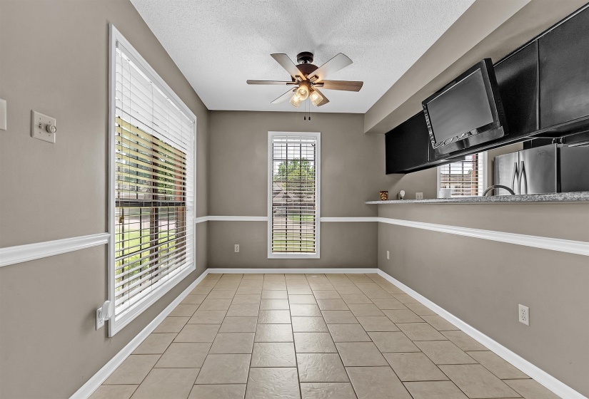 Unfurnished dining area with a ceiling fan, a textured ceiling, and light tile patterned floors