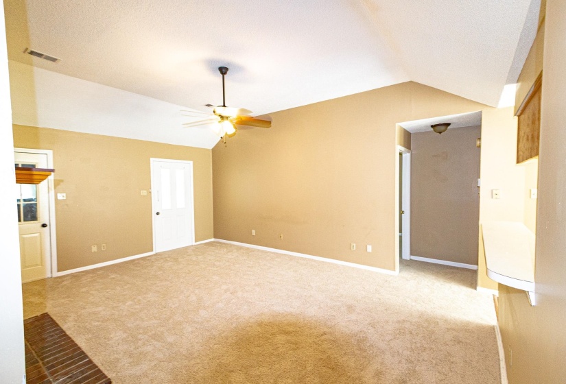 Unfurnished living room with vaulted ceiling, light colored carpet, and ceiling fan