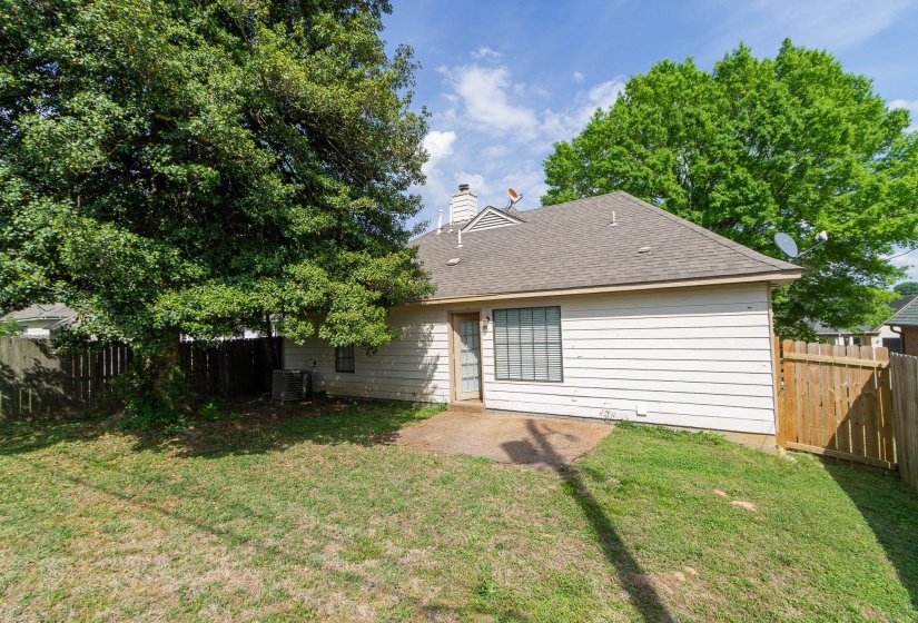 Back of house featuring a fenced backyard, roof with shingles, and a chimney