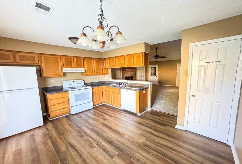 Kitchen featuring suspended lighting, white appliances, dark countertops, ceiling fan, and a textured ceiling