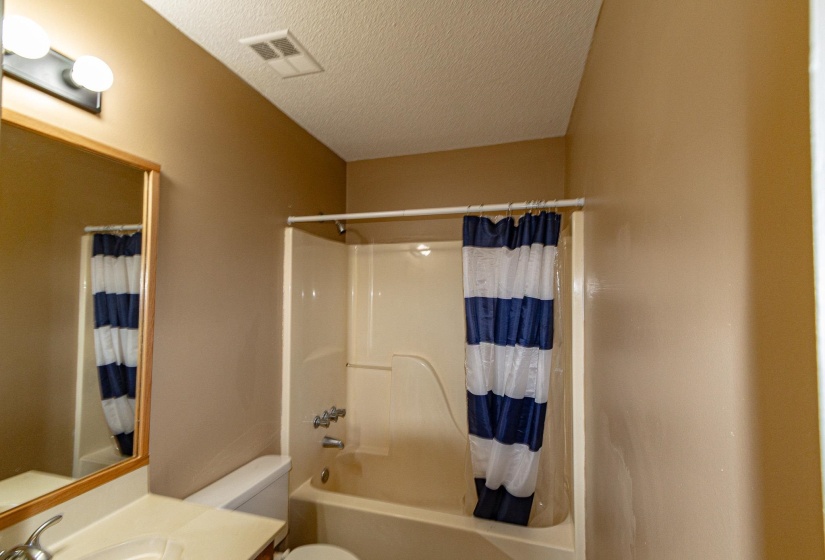 Full bathroom featuring vanity, shower / tub combo, and a textured ceiling
