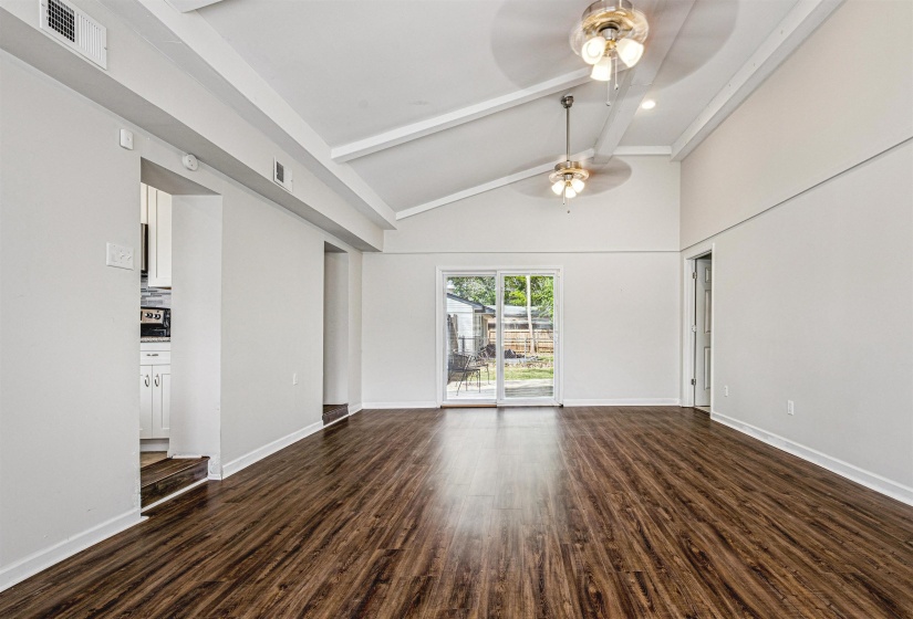 Unfurnished living room featuring dark wood-style flooring, vaulted ceiling, and a ceiling fan