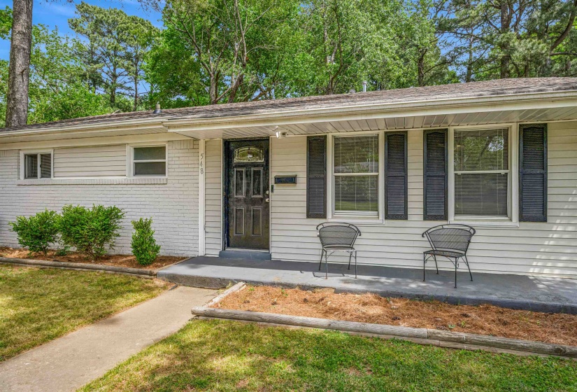 View of front of home featuring brick siding, covered porch, and a front lawn
