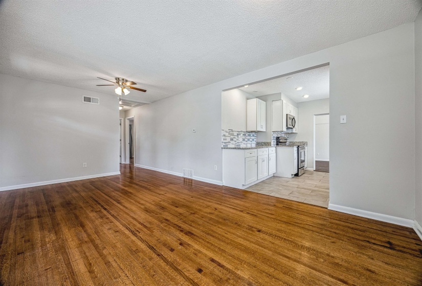 Unfurnished living room featuring light wood-style floors, a ceiling fan, and a textured ceiling