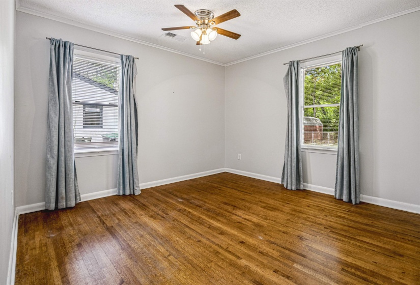 Unfurnished room with dark wood finished floors, ceiling fan, crown molding, a textured ceiling, and plenty of natural light