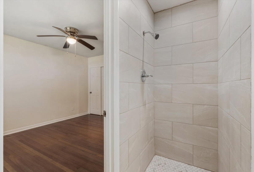 Bathroom with a shower stall, a ceiling fan, and wood finished floors