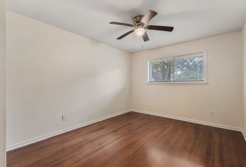 Spare room featuring dark wood-type flooring and ceiling fan