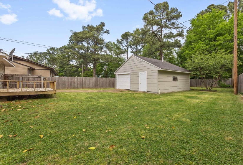 Fenced backyard with an outdoor structure, a garage, and a deck
