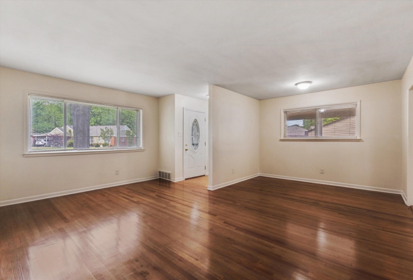 Spare room featuring dark wood-style flooring and baseboards