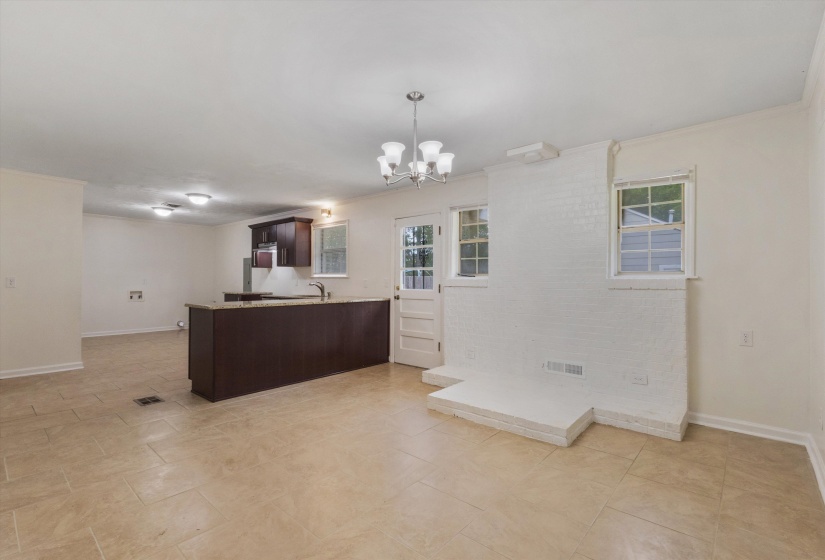 Kitchen featuring dark wood finish cabinets, a peninsula, ornamental molding, a chandelier, and light stone countertops