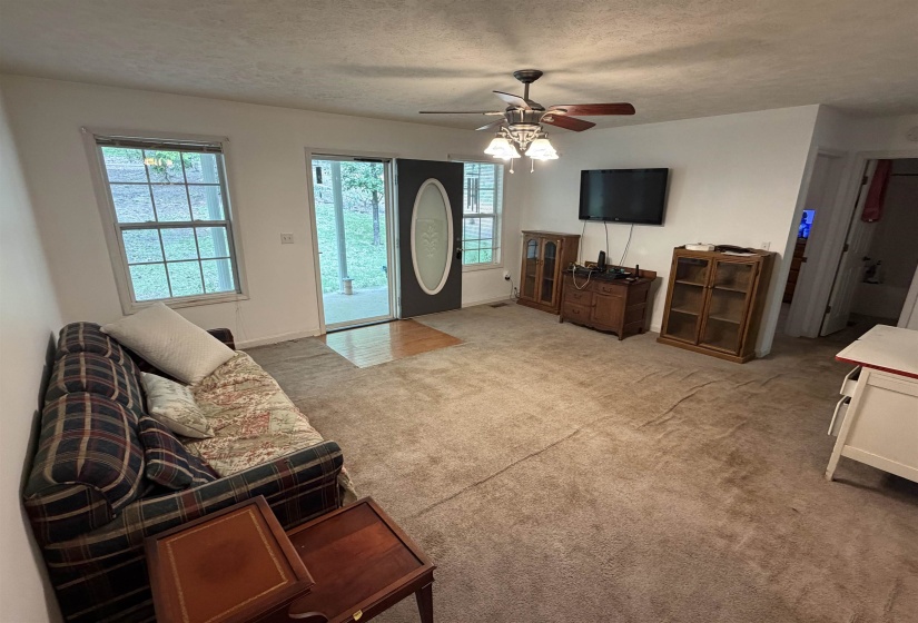 Living room featuring carpet flooring, a ceiling fan, a textured ceiling, and healthy amount of natural light