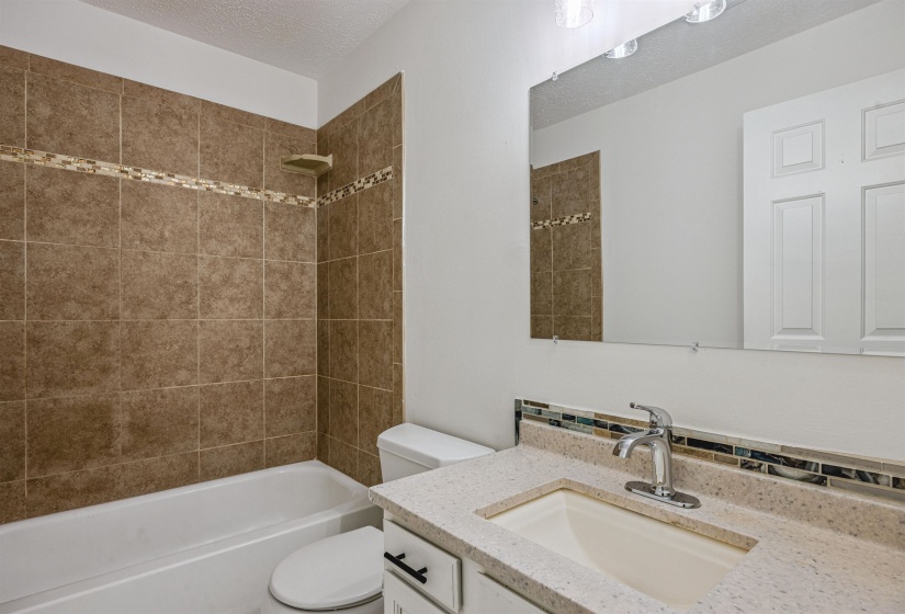 Bathroom featuring vanity, a textured ceiling, and  shower combination