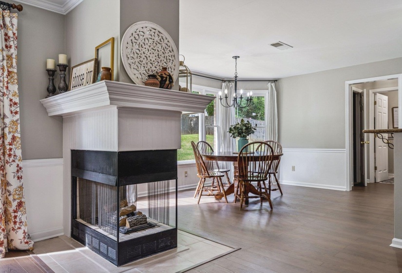 Dining room featuring wood finished floors, suspended lighting, and a multi sided fireplace