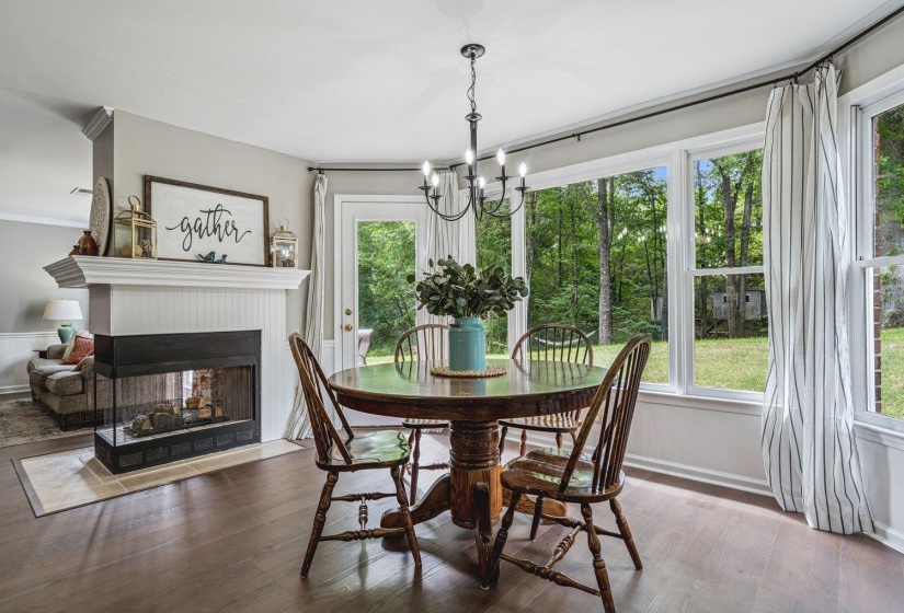 Dining room with hardwood / wood-style flooring, ornamental molding, a chandelier, and a multi sided fireplace