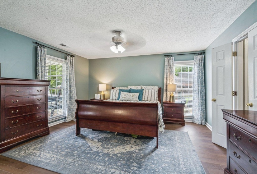 Bedroom with dark wood-style flooring, multiple windows, a ceiling fan, and a textured ceiling